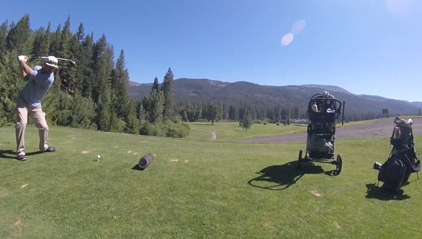 father playing golf with young son on a forest course